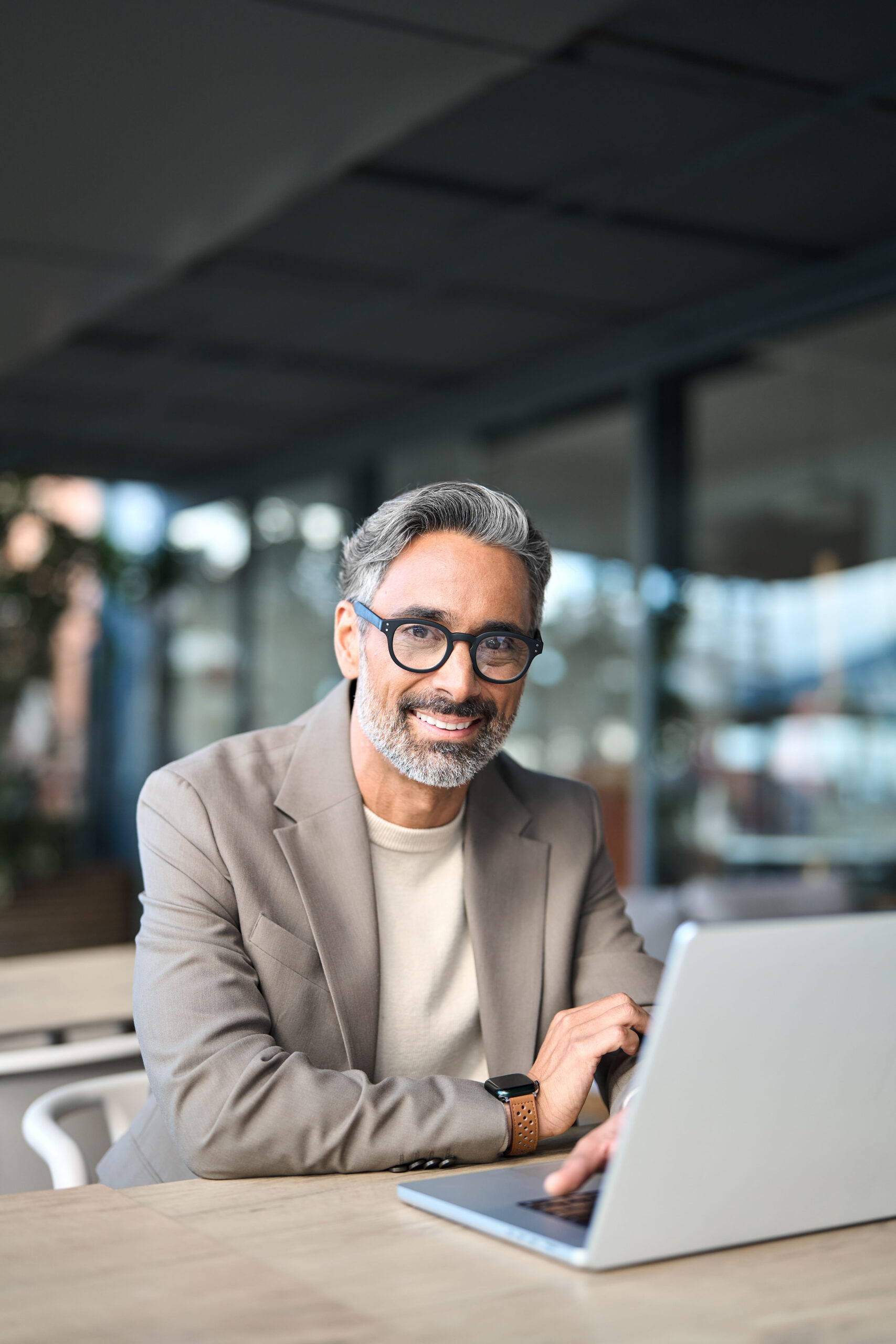 Happy middle aged business man sitting at table using laptop. Portrait.